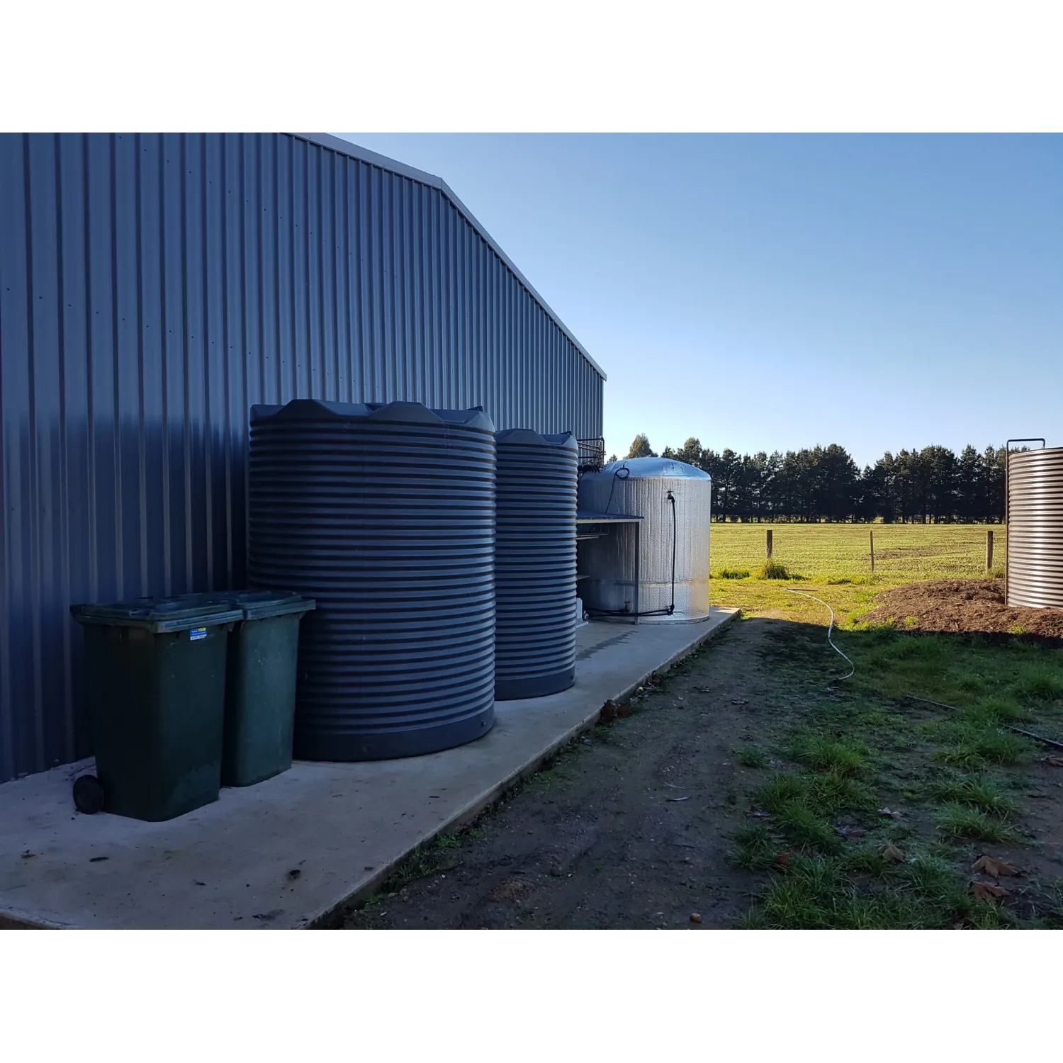 Two 4600 Ltr Corrugated Rainwater Tanks matching Colorbond® colours on a farm shed