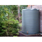 4600 Ltr Corrugated Rainwater Tank on gravel base with ferns and brick wall