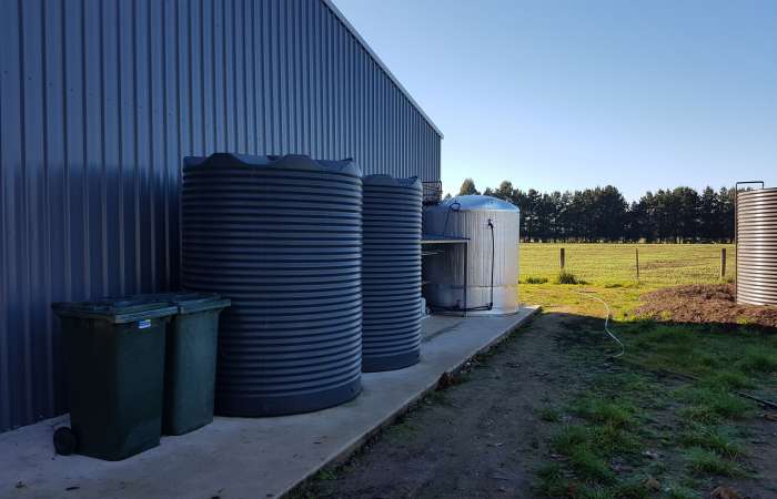 Two 4600 Ltr Corrugated Rainwater Tanks matching Colorbond® colours on a farm shed