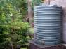 4600 Ltr Corrugated Rainwater Tank on gravel base with ferns and brick wall