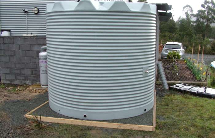 11250 Ltr Corrugated Rainwater Tank in Armour Grey sitting on gravel base, matching house Colorbond® colours.
