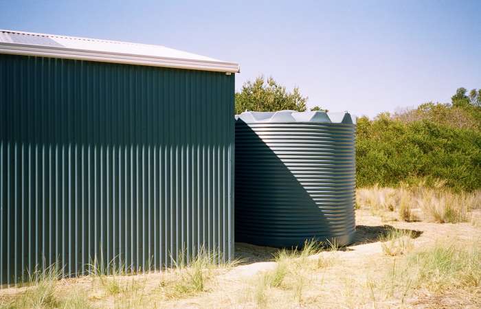 11250 Ltr Corrugated Rainwater Tank against vertical corrugation on green shed