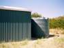 11250 Ltr Corrugated Rainwater Tank against vertical corrugation on green shed
