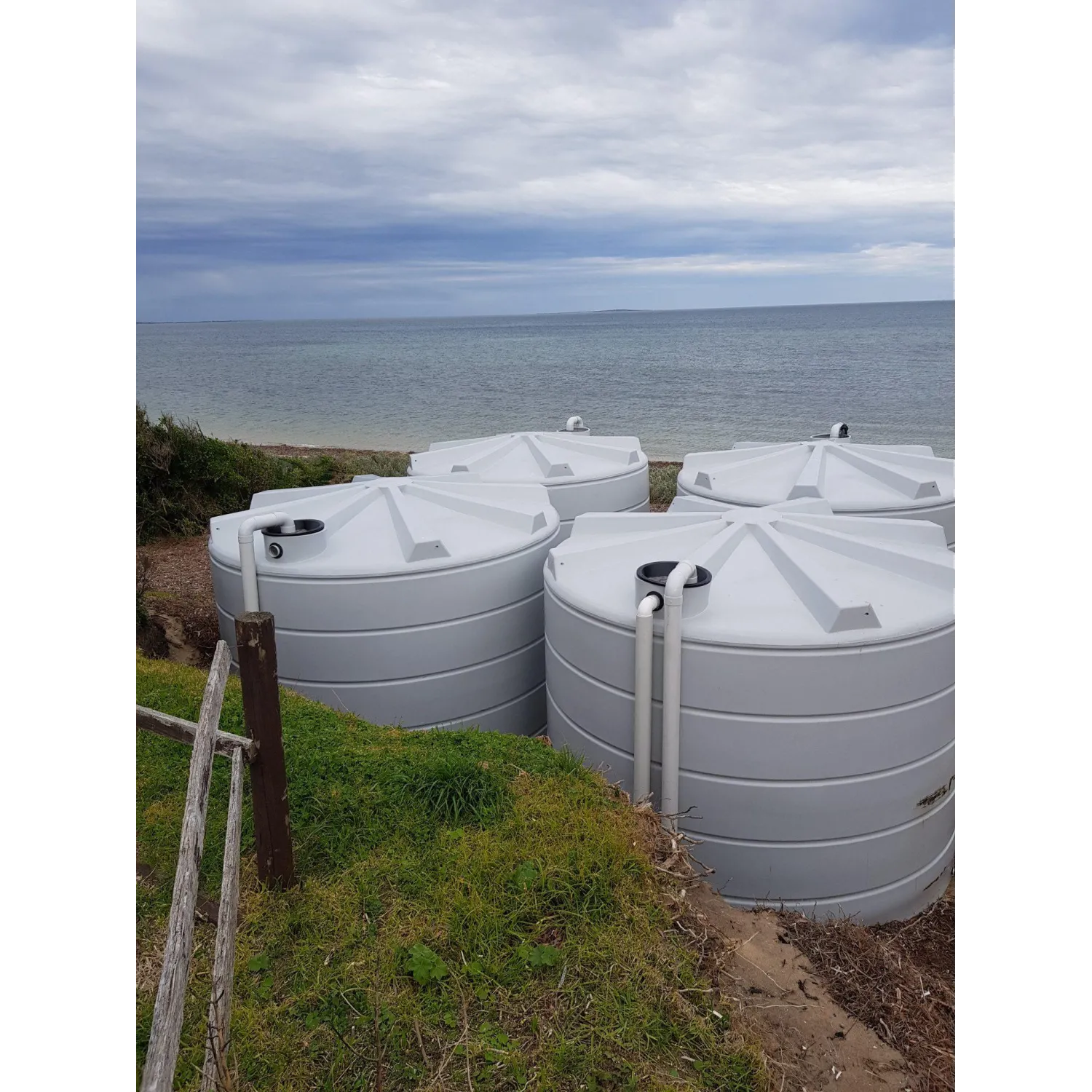 Four 22000 Ltr Panelled Wall Rainwater Tanks sitting beach side.