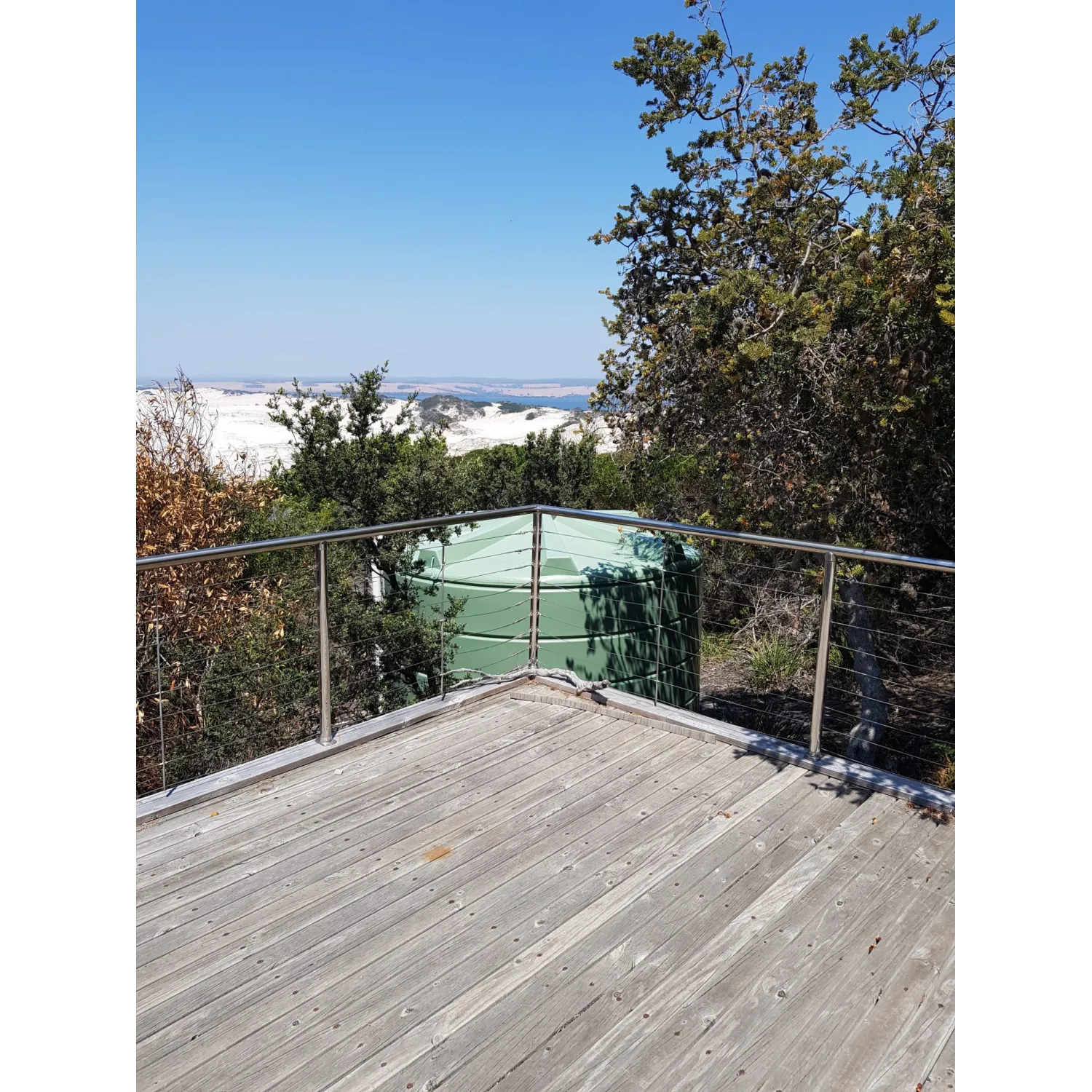 Orion Australia 22000 Ltr Panelled Wall Rainwater Tank accompanying a Tasmanian beach view from a timber deck.