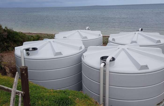 Four 22000 Ltr Panelled Wall Rainwater Tanks sitting beach side.