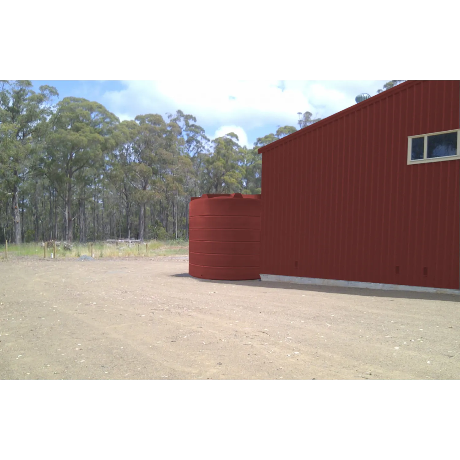 26000 Ltr Panelled Wall Rainwater Tank on gravel next to red shed