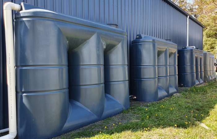 Three 3000 Ltr Slimline Rainwater Tanks joined by tap/valve next to blue shed