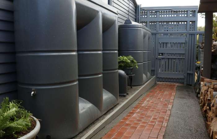 Two Orion Australia 3000ltr Slimline Tanks in Woodland Grey on weatherboard house with brick path
